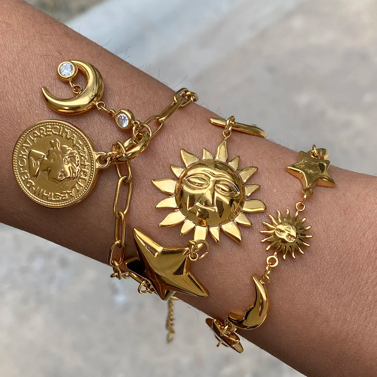 Gold celestial motif bracelet featuring sun, moon, star charms, and coin details on wrist