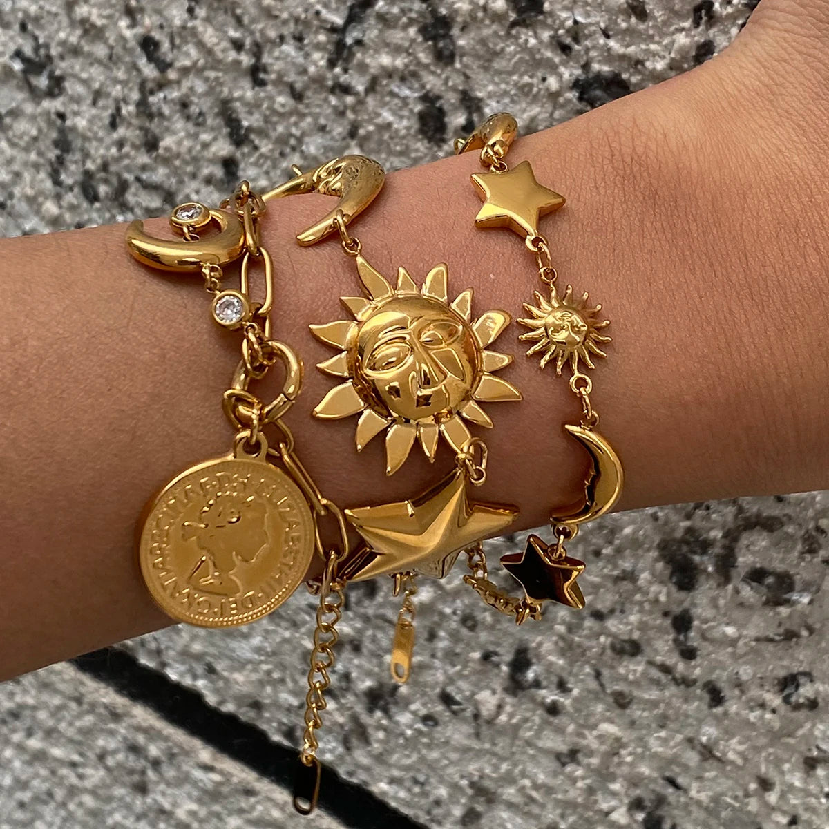 Gold celestial motif bracelet featuring sun, moon, stars, and coin charms on wrist