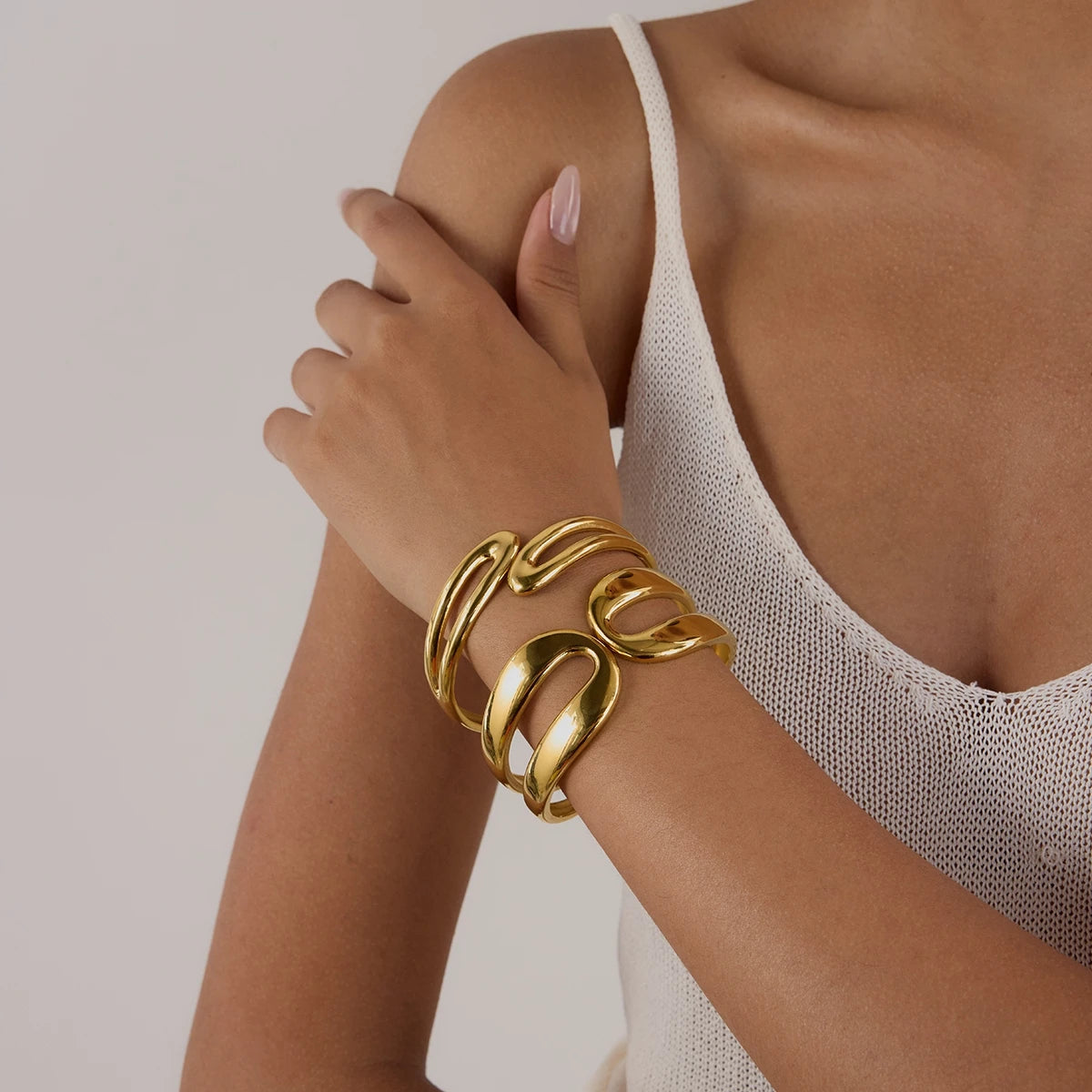 Woman wearing chunky wavy gold bracelets showcasing everyday gold jewelry style