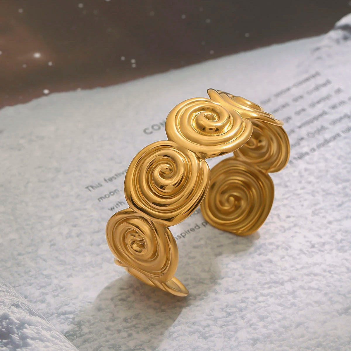Adjustable gold bracelet with spiral design links on textured paper background