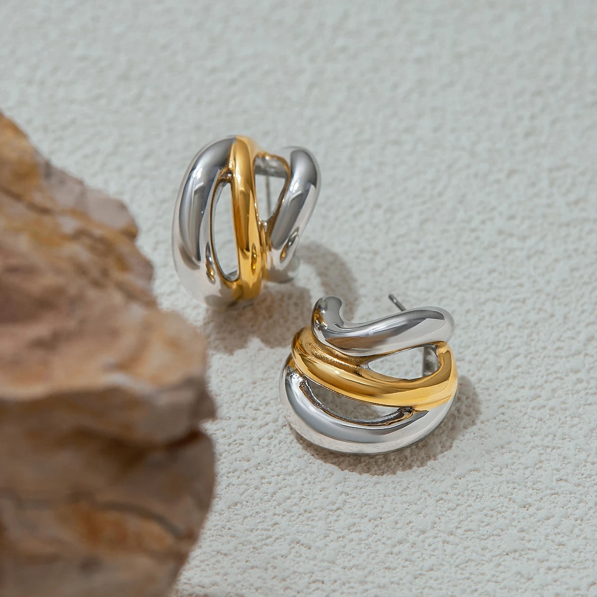 Gold and silver twisted hoop luxury stud earrings on textured surface by A minha loja