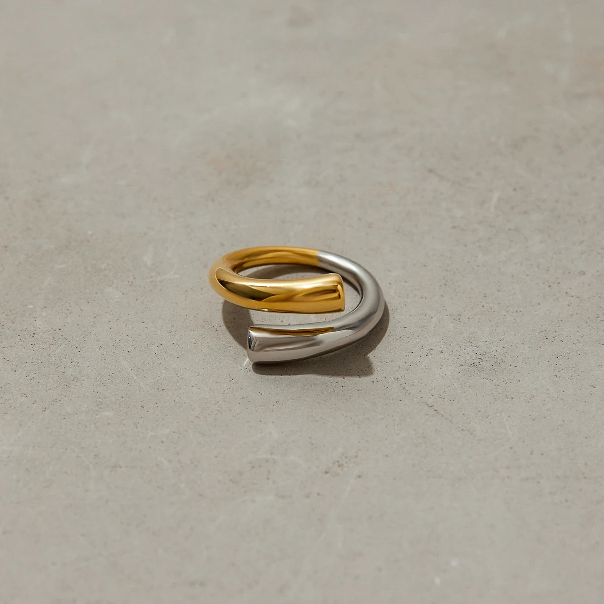 Two-tone stainless steel line ring with gold and silver finish on concrete surface