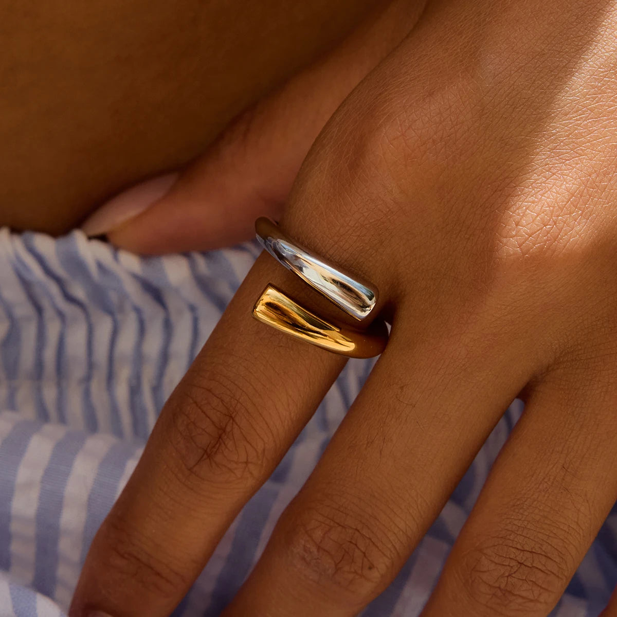 Close-up of a hand wearing a stylish stainless steel line ring with silver and gold tones