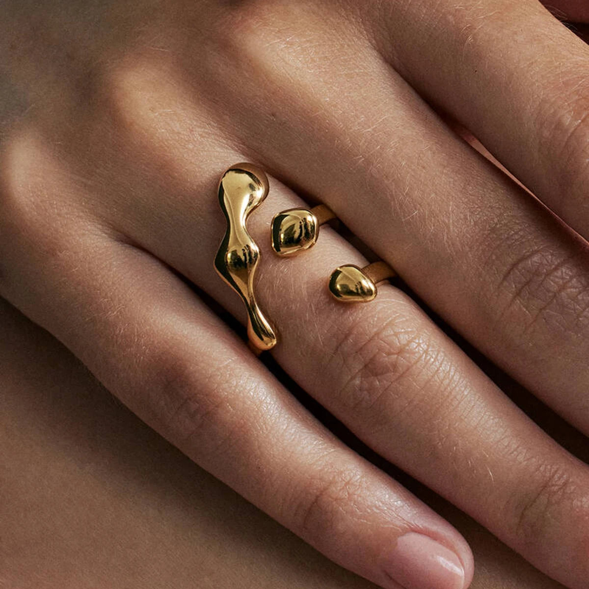 Close-up of hand wearing artistic statement gold rings with unique abstract shapes