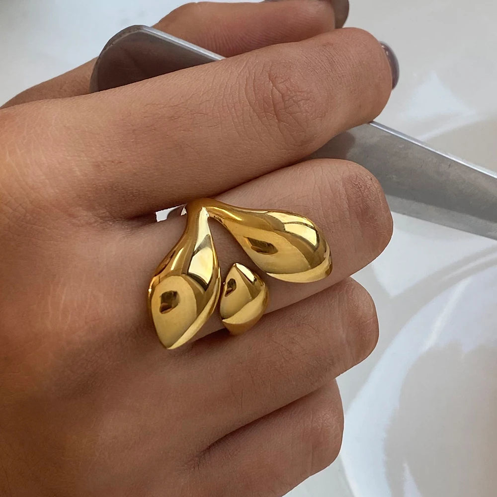 Close-up of a hand wearing chunky statement gold rings with a modern, abstract design