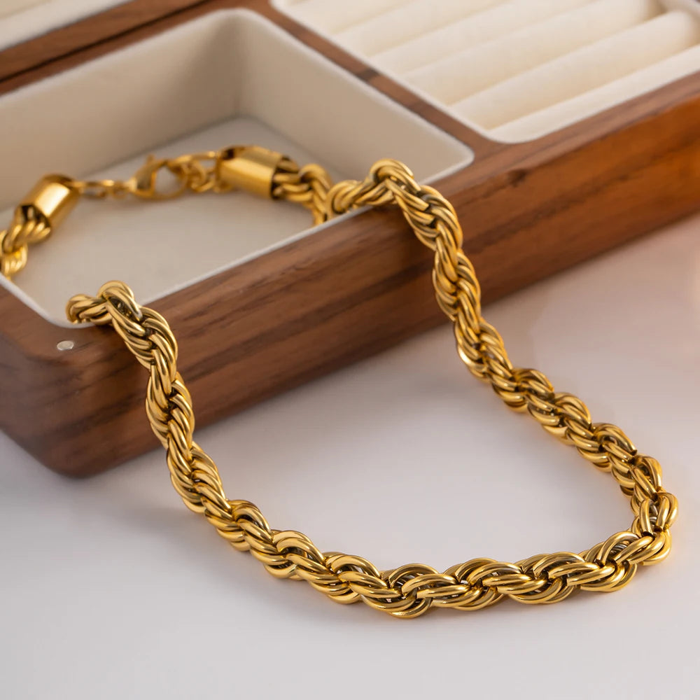 Bold gold statement necklace with twisted chain design displayed next to a wooden jewelry box