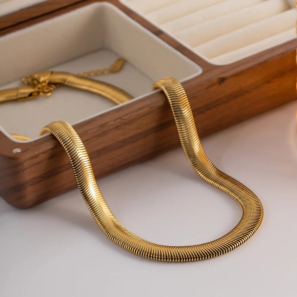 Bold gold statement necklace with thick chain links displayed on a wooden jewelry box