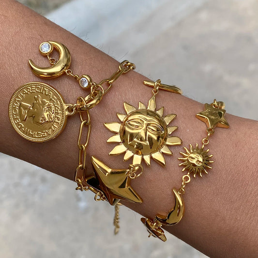 Gold celestial motif bracelet featuring sun, moon, star charms, and coin details on wrist