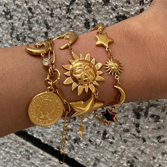 Gold celestial motif bracelet featuring sun, moon, stars, and coin charms on wrist