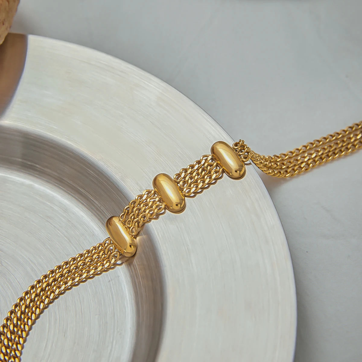 Fashionable gold bracelet with multiple chains and smooth gold beads on decorative plate