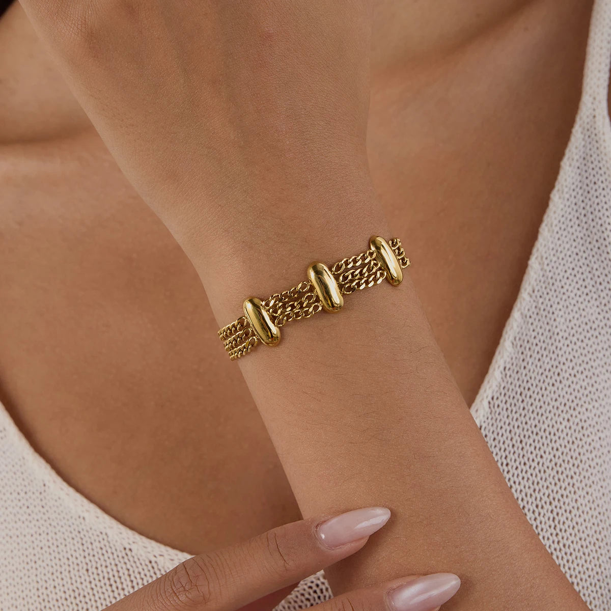 Fashionable gold bracelet with linked design worn on wrist with light skin tone