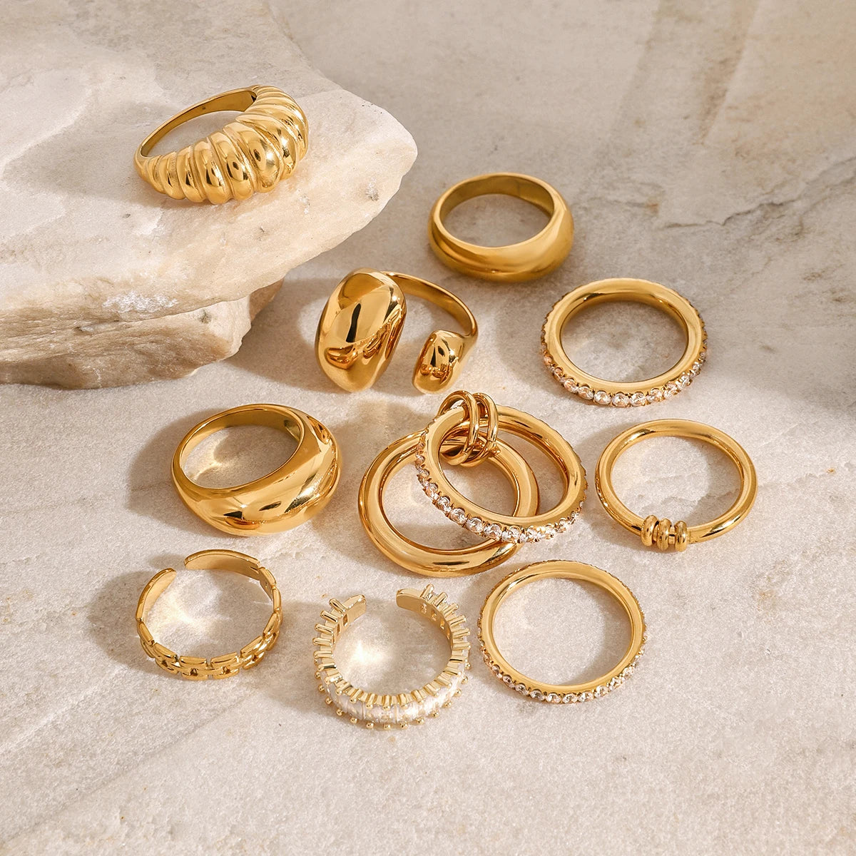 Set of fashionable stackable rings in gold tone with various designs including plain, textured, and rhinestone accents