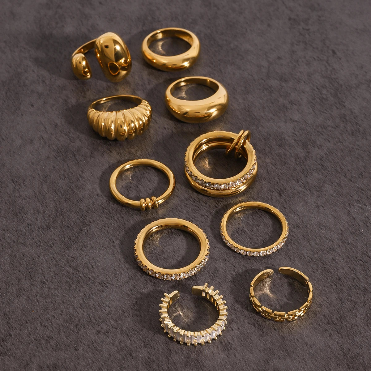 A minha loja Fashionable Stackable Rings in gold with various designs and embedded stones on a textured background