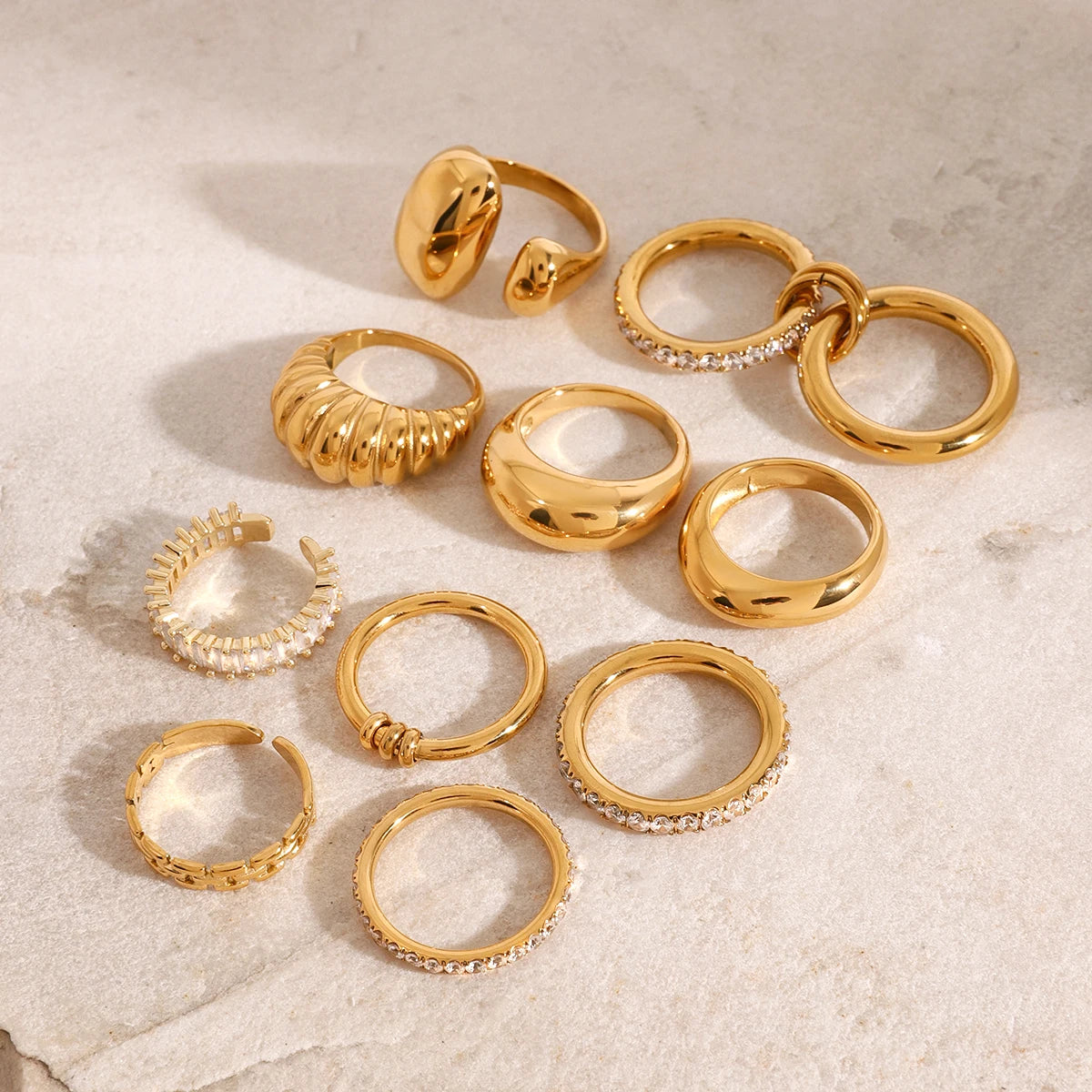 Set of Fashionable Stackable Rings in gold with various designs including smooth, textured, and rhinestone accents