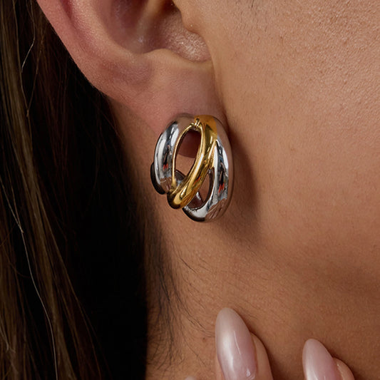 Close-up of ear with gold and silver twisted luxury stud earrings worn by woman