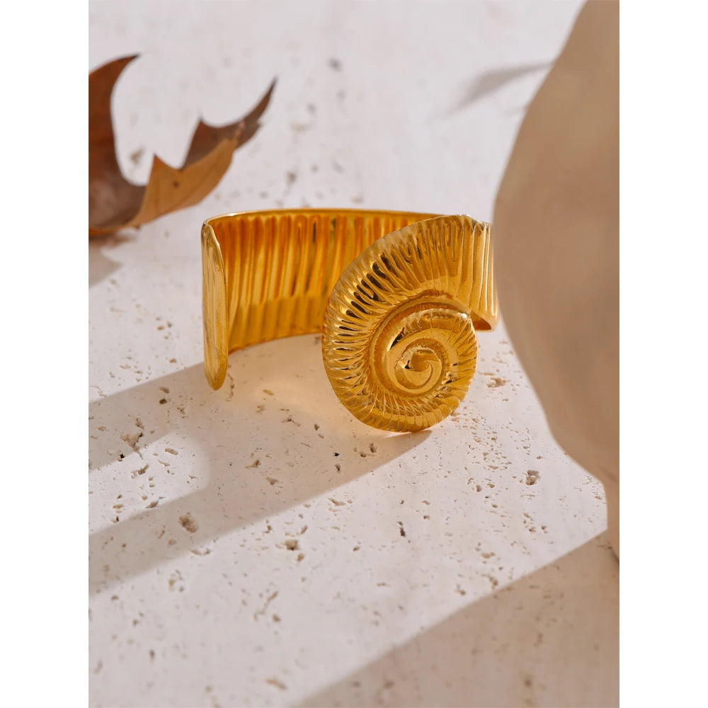 Gold waterproof open bangle with spiral design on textured stone surface