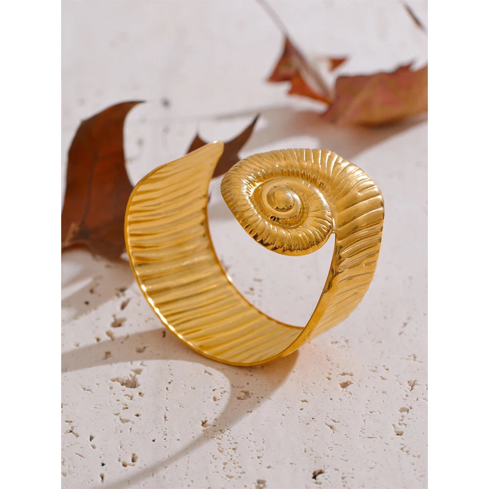 Gold textured waterproof open bangle with a spiral design displayed on stone surface